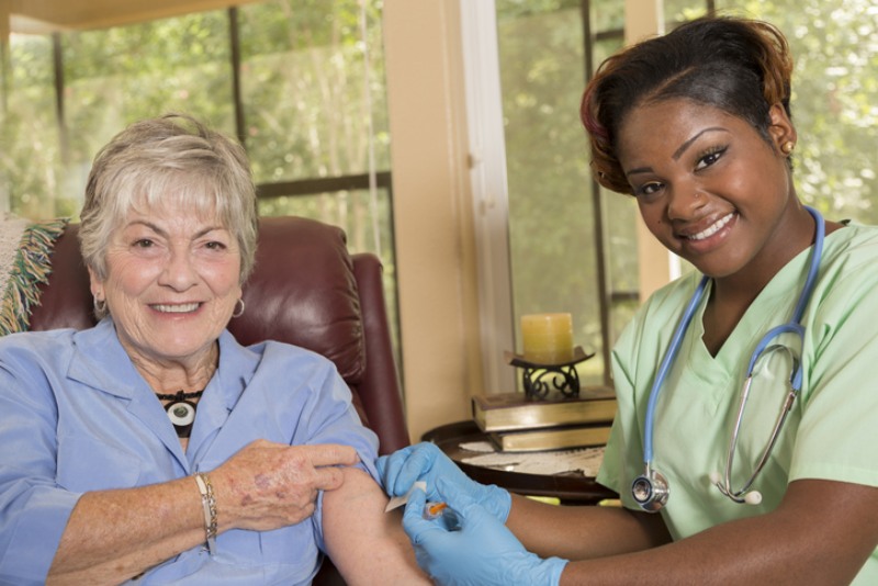 Caregiver giving older woman an IV