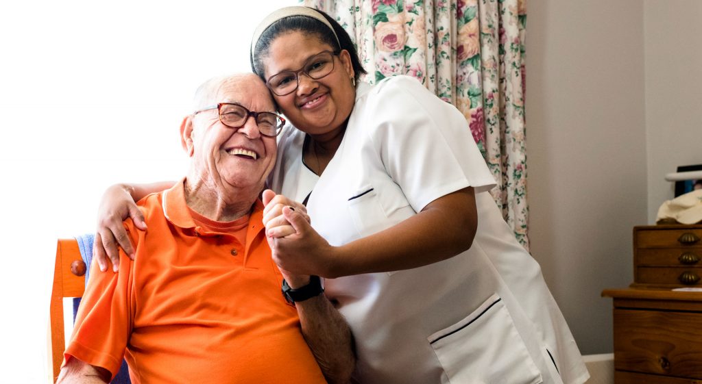 nurse hugging a senior citizen in a nursing home