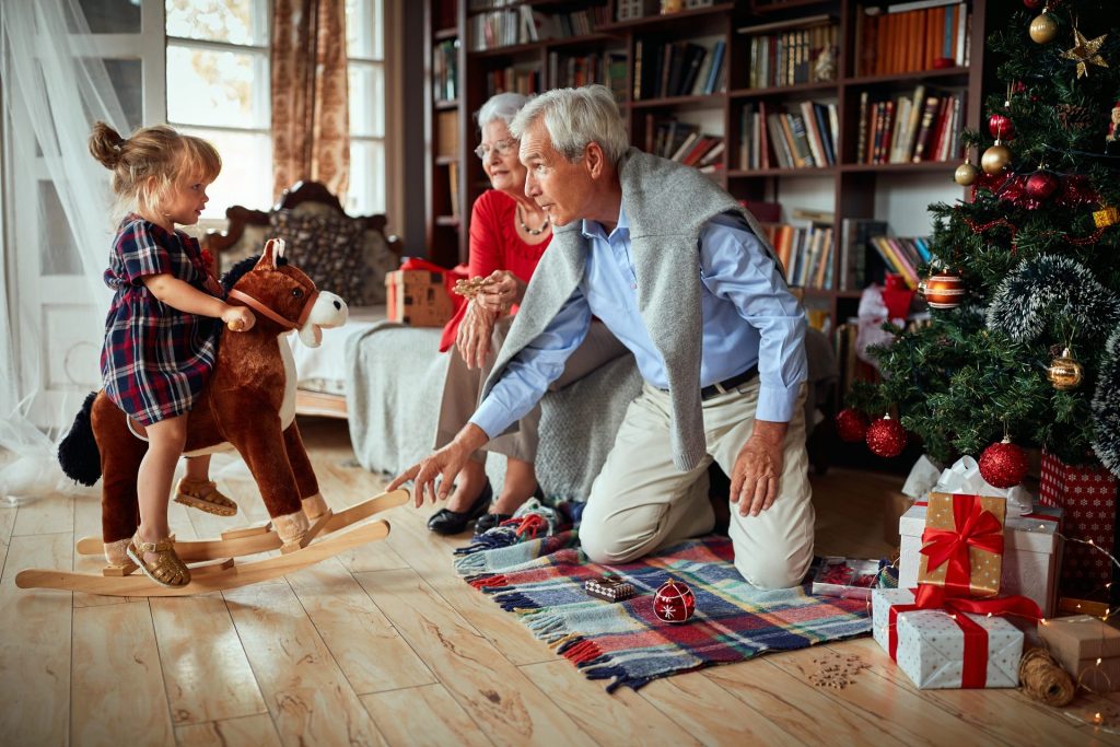 senior man and woman playing with granddaughter on rocking horse