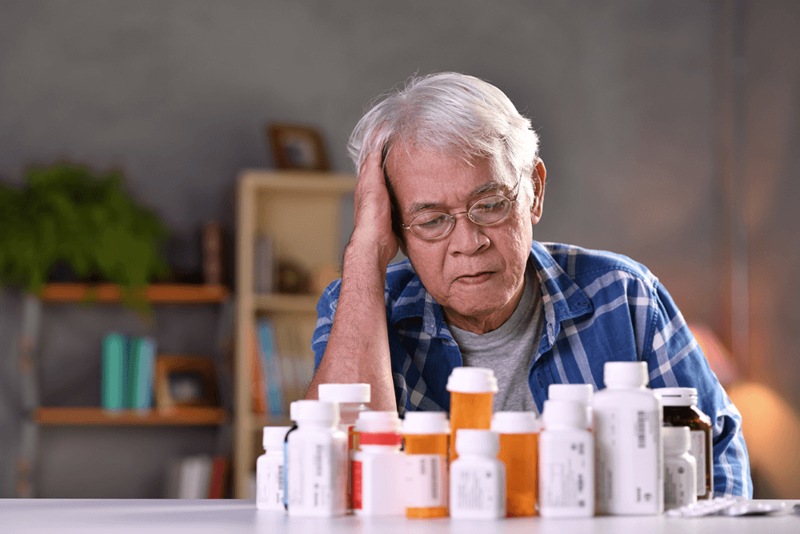 Older man looks at pill bottles confused