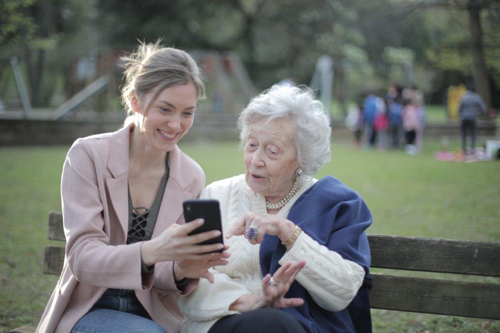 The girls showing mobile to her grandmother in park at Rockville, MD