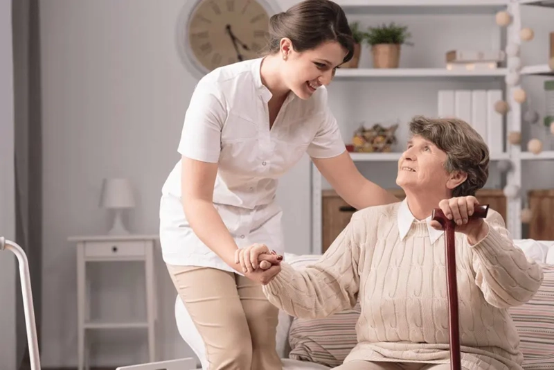 The Smithlife home care staff helping to the old women to sit on couch at Rockville MD