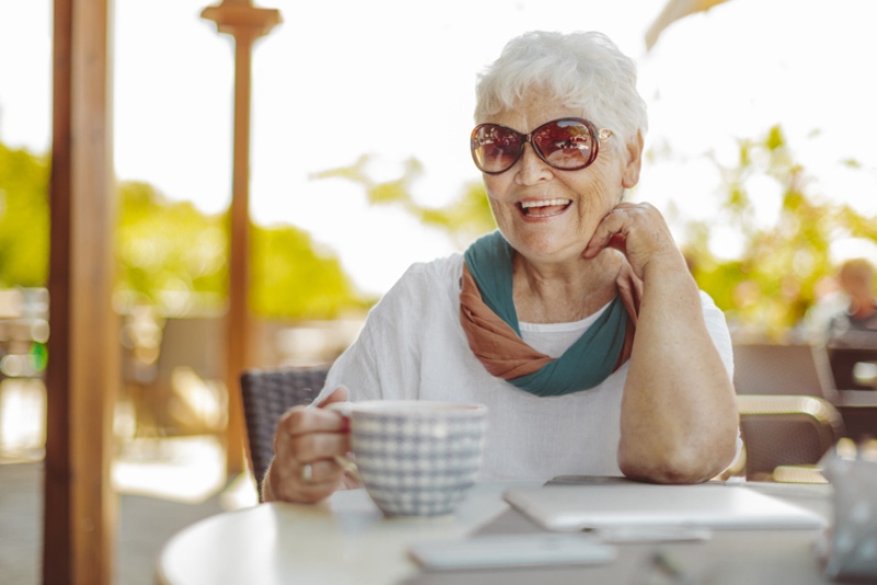 Senior with sunglasses smiling at a table