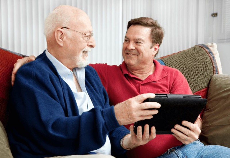 Adult looking at a senior holding a tablet