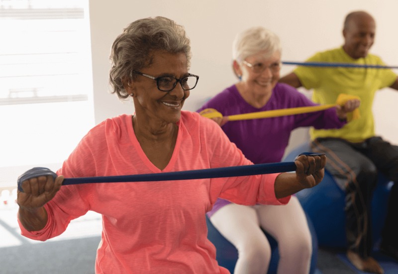 Elderly woman exercising with resistance bands at home