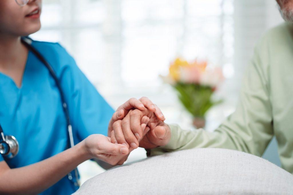 Nurse holding hospice client's hand