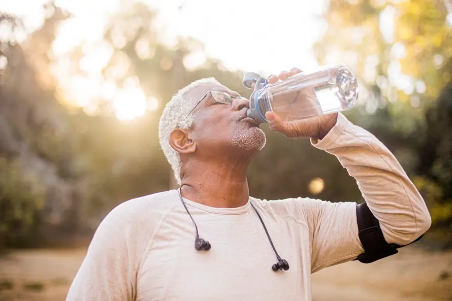 Older adult man takes a drink of water during his workout