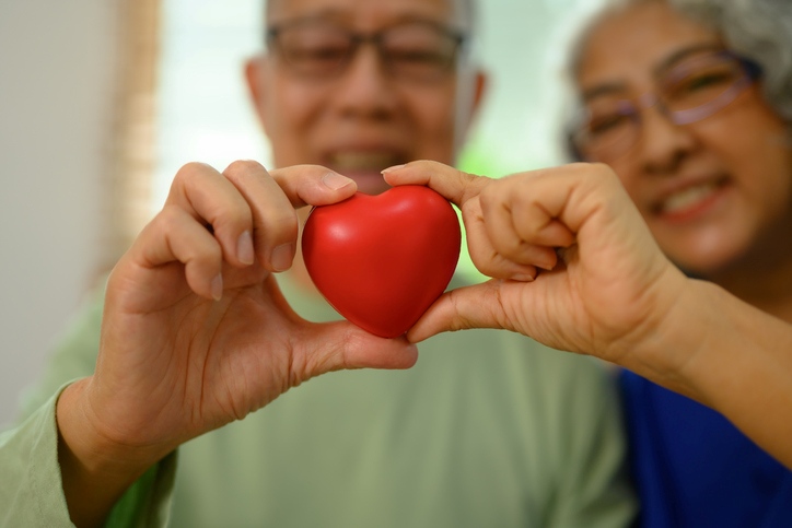 A senior couple holding a red heart together, smiling in Maryland & Washington, DC